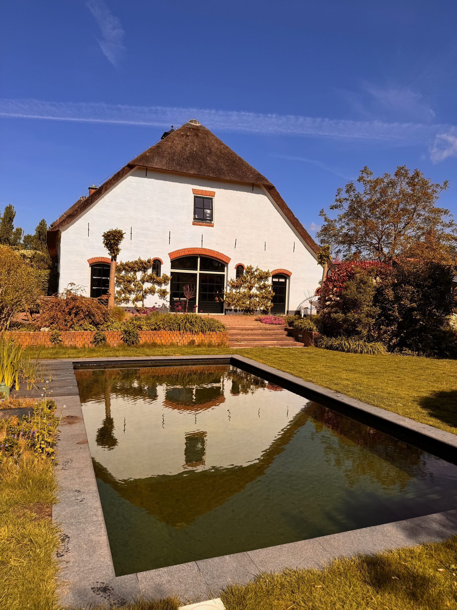 Spiegelvijver in de tuin met de rietgedekte boerderij weerspiegeld